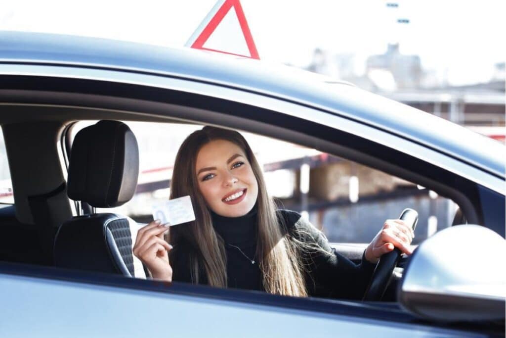 Mulher sorridente exibindo carteira de motorista no carro.