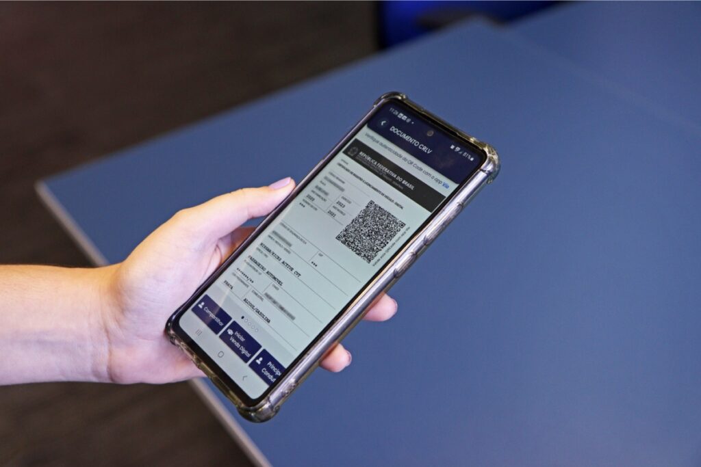 Mão segurando smartphone com tela de QR Code.